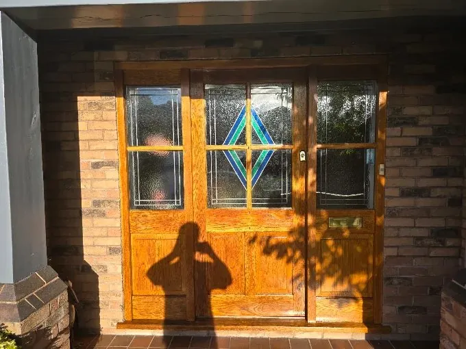 Varnished hardwood front door with stained glass
