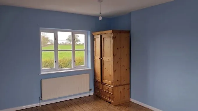 Bedroom painted slate blue, looking out over fields